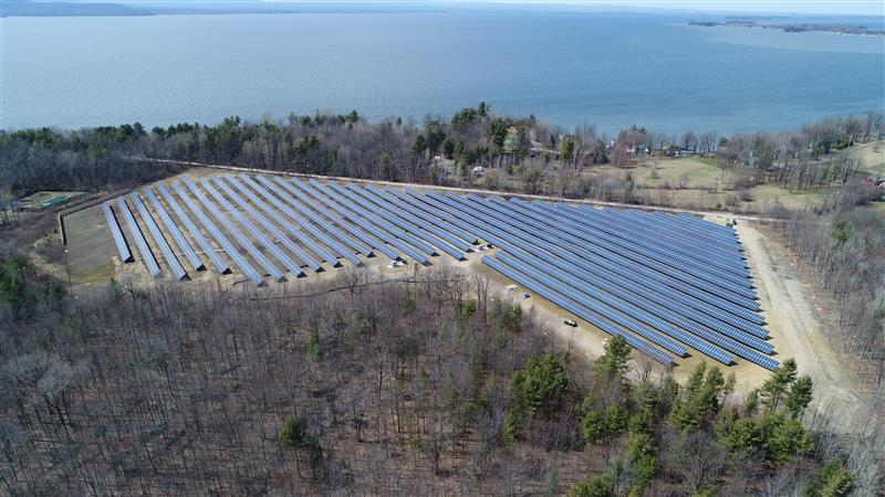 Aerial view of a utility-scale solar array at sunrise in rolling hills